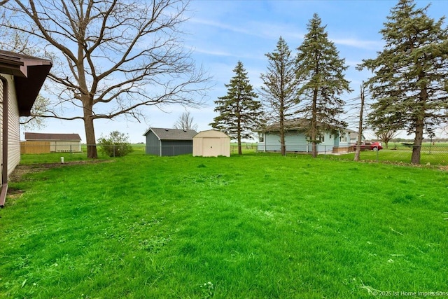 view of yard featuring an outbuilding, fence, and a storage shed