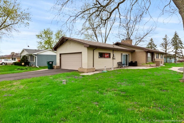view of front of house featuring an attached garage, a front yard, driveway, and a chimney