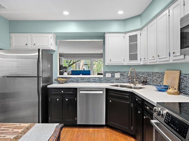 kitchen with a sink, dark cabinetry, white cabinets, and appliances with stainless steel finishes