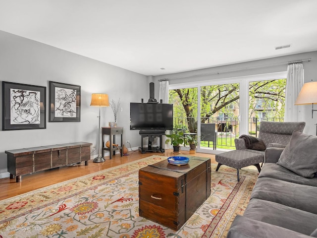 living room with baseboards, visible vents, and wood finished floors