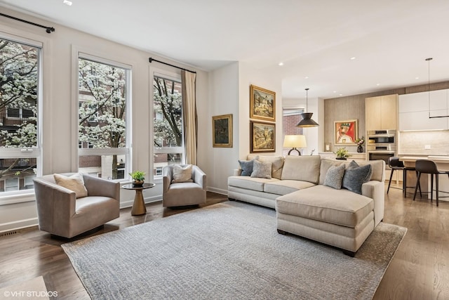 living area with dark wood-type flooring, recessed lighting, baseboards, and a healthy amount of sunlight