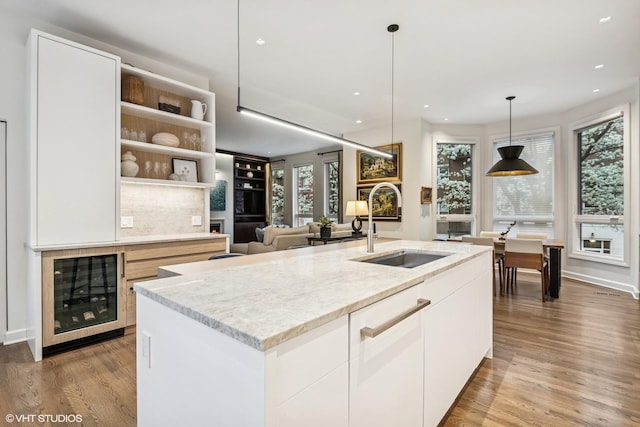 kitchen with a sink, recessed lighting, beverage cooler, and wood finished floors
