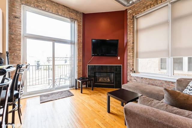 949 N Willard Ct Unit 302, Chicago, IL 60642 - living area with light wood-style floors, a glass covered fireplace, and brick wall