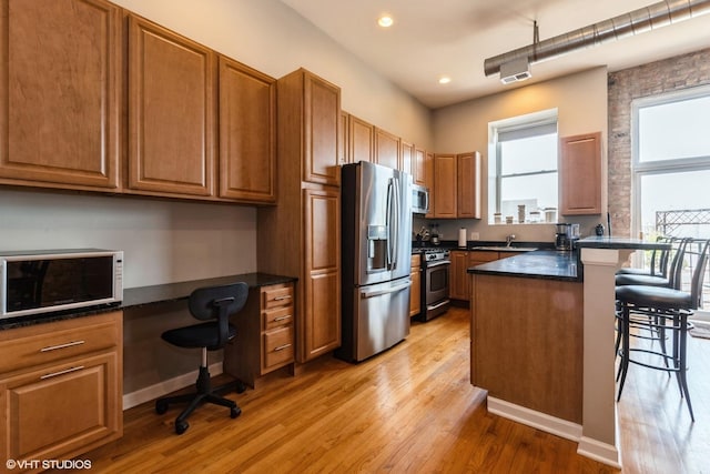 949 N Willard Ct Unit 302, Chicago, IL 60642 - kitchen with appliances with stainless steel finishes, a kitchen breakfast bar, recessed lighting, light wood-type flooring, and brown cabinets