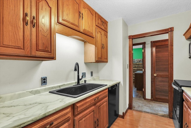 kitchen featuring brown cabinets, a sink, light wood-style floors, light countertops, and black appliances