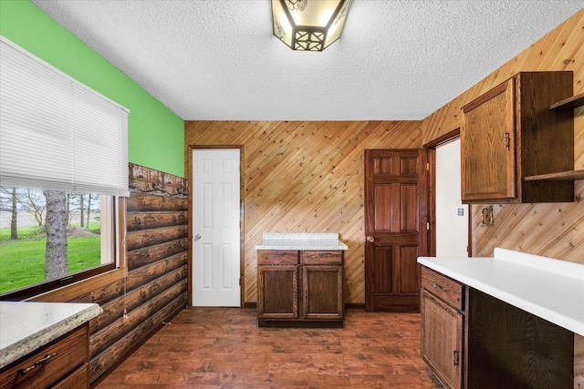 kitchen with light countertops, rustic walls, and a textured ceiling