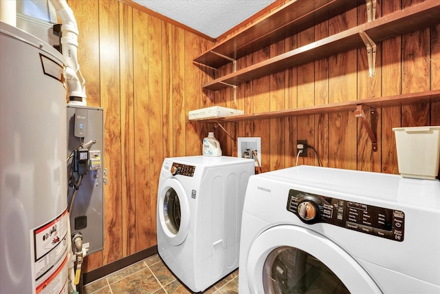 laundry area featuring laundry area, wood walls, a textured ceiling, independent washer and dryer, and water heater