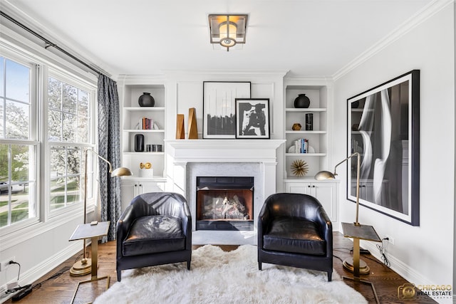 living area featuring baseboards, plenty of natural light, crown molding, and a glass covered fireplace