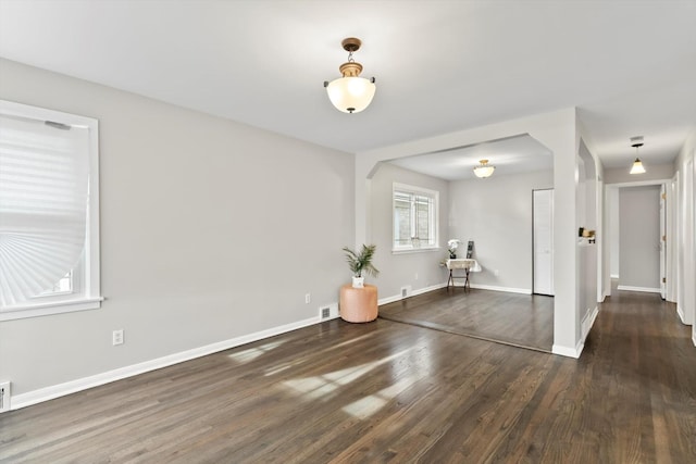 empty room with baseboards, visible vents, and wood finished floors