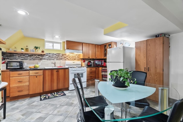 kitchen with decorative backsplash, brown cabinets, exhaust hood, and white appliances
