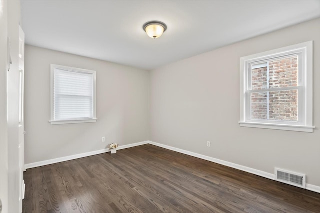 spare room featuring visible vents, baseboards, dark wood-style flooring, and a healthy amount of sunlight