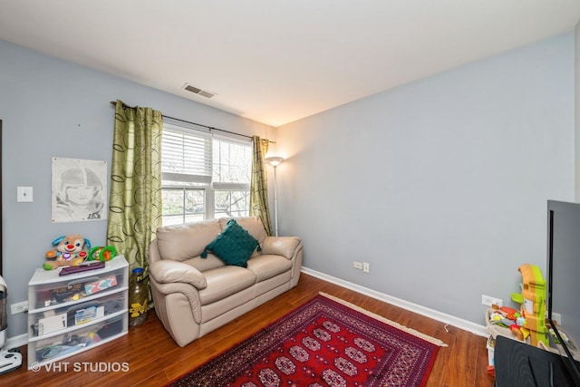 living area with visible vents, baseboards, and wood finished floors