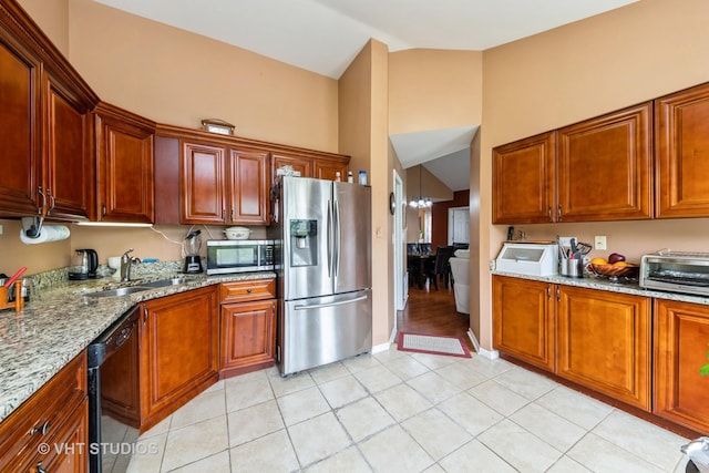 kitchen featuring vaulted ceiling, a sink, light stone counters, stainless steel appliances, and light tile patterned flooring