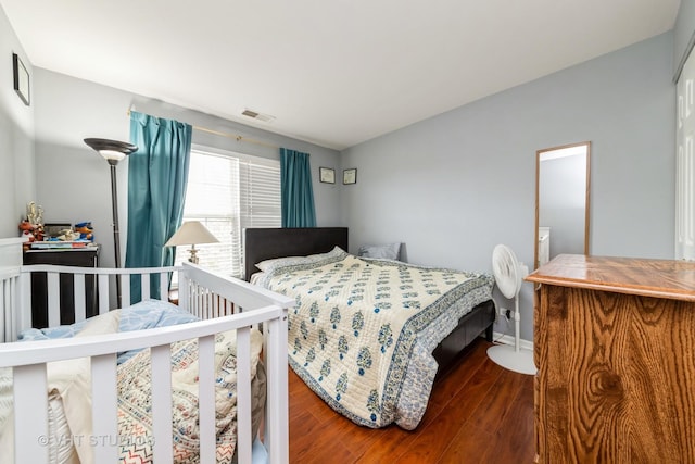 bedroom featuring baseboards, visible vents, and wood finished floors