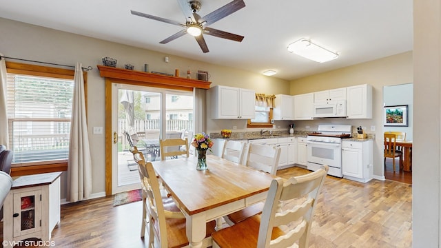 kitchen featuring a sink, white appliances, light stone counters, light wood finished floors, and white cabinetry