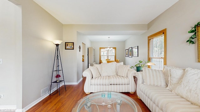 living area featuring baseboards, a chandelier, visible vents, and wood finished floors