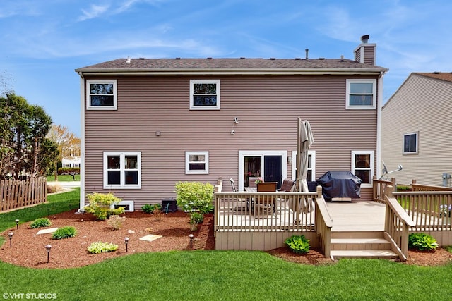 rear view of house featuring a lawn, a chimney, and a wooden deck