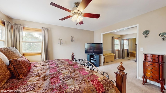 bedroom featuring light colored carpet, a ceiling fan, and multiple windows