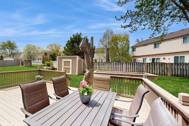 deck with an outdoor structure, a lawn, a fenced backyard, and a shed