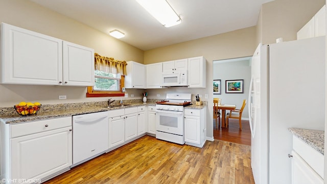 kitchen featuring light wood-style flooring, white appliances, light stone counters, a sink, and white cabinetry