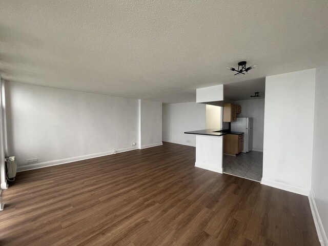 6700 S S Shore Dr Unit 21B, Chicago, IL 60649 - unfurnished living room featuring dark wood finished floors, a textured ceiling, baseboards, and radiator heating unit