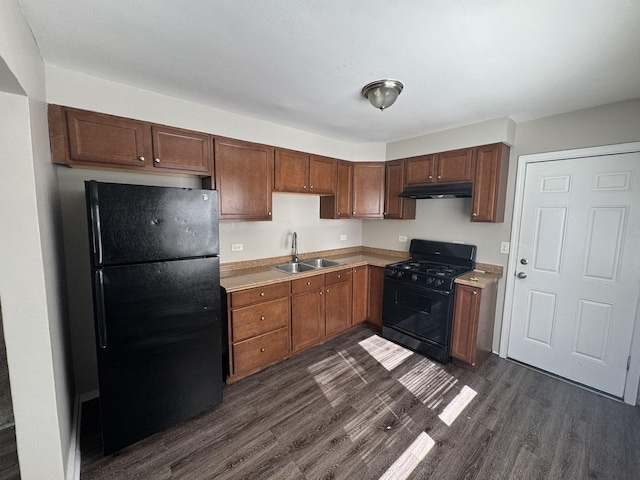 kitchen with a sink, black appliances, dark wood-style floors, and under cabinet range hood