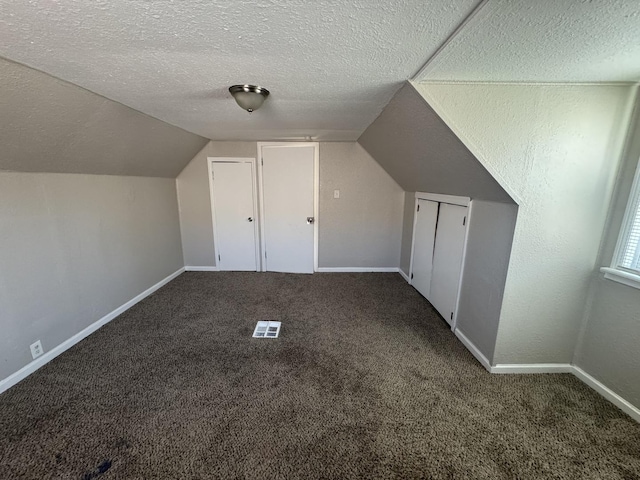 bonus room with visible vents, lofted ceiling, baseboards, a textured ceiling, and carpet flooring