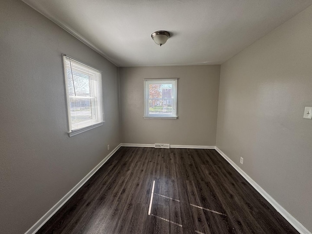 unfurnished room with visible vents, baseboards, and dark wood-style floors
