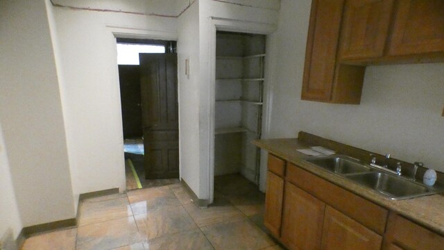 1910 S Spaulding Ave, Chicago, IL 60623 - kitchen featuring a sink, baseboards, brown cabinetry, and light tile patterned flooring