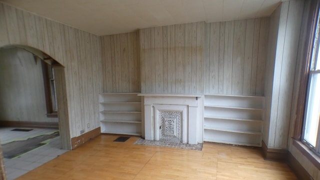 1910 S Spaulding Ave, Chicago, IL 60623 - unfurnished living room with wood walls, a fireplace with flush hearth, light wood-style flooring, and visible vents