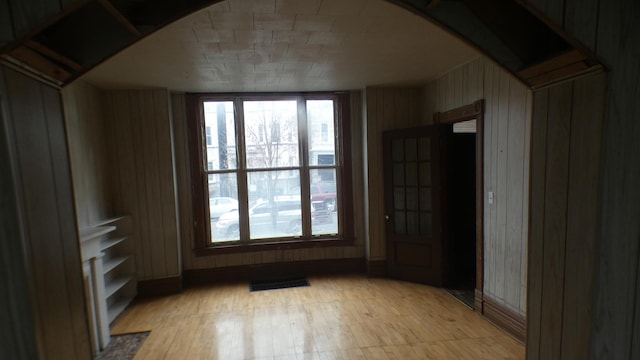 1910 S Spaulding Ave, Chicago, IL 60623 - unfurnished room with visible vents, wood walls, a healthy amount of sunlight, and light wood finished floors