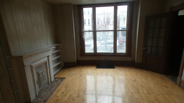 1910 S Spaulding Ave, Chicago, IL 60623 - unfurnished living room with visible vents, a fireplace with flush hearth, light wood-style flooring, and wooden walls