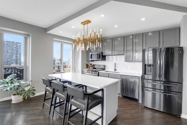 kitchen featuring a center island, a sink, an inviting chandelier, stainless steel appliances, and dark wood-type flooring