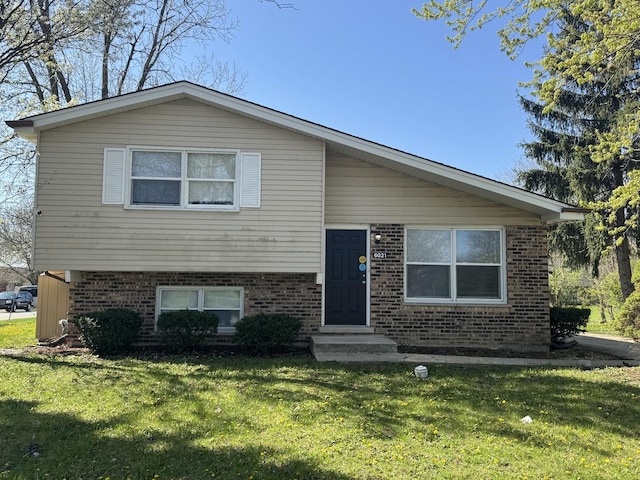 tri-level home featuring a front yard and brick siding