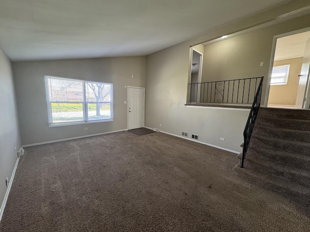 unfurnished living room featuring dark carpet, baseboards, stairs, and lofted ceiling