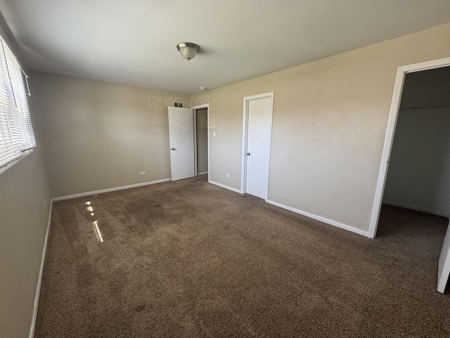 unfurnished bedroom with baseboards, carpet flooring, a spacious closet, and a closet