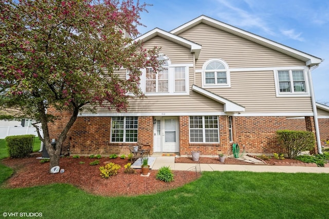 traditional-style home featuring a front yard and brick siding
