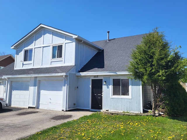 traditional-style home with an attached garage, driveway, a shingled roof, and a front lawn