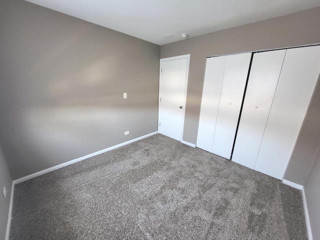 unfurnished bedroom featuring baseboards, carpet, and a closet