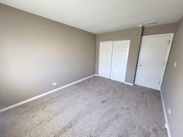 unfurnished bedroom with visible vents, carpet flooring, baseboards, and a closet