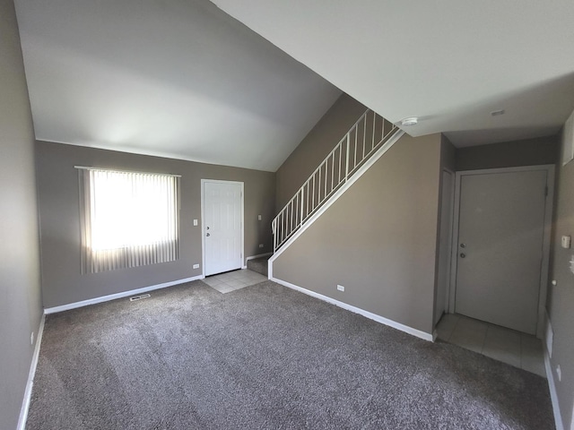 carpeted entrance foyer featuring tile patterned flooring, baseboards, lofted ceiling, visible vents, and stairway