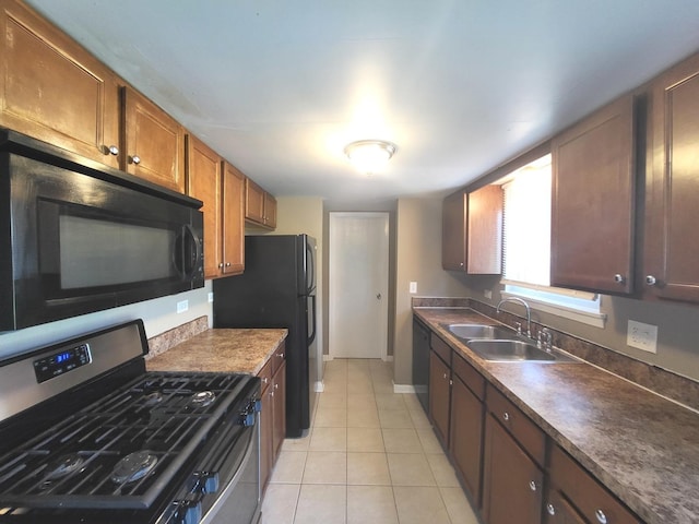 kitchen featuring brown cabinetry, a sink, light tile patterned floors, baseboards, and black appliances