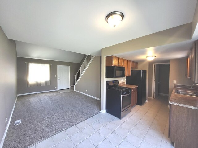 kitchen with visible vents, baseboards, a sink, light tile patterned floors, and black appliances