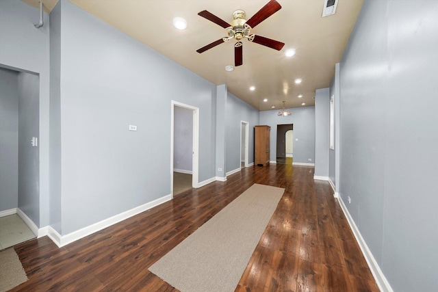 hallway with arched walkways, baseboards, dark wood-style flooring, and visible vents