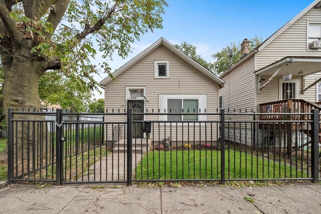 back of house featuring a gate, a fenced front yard, and a yard