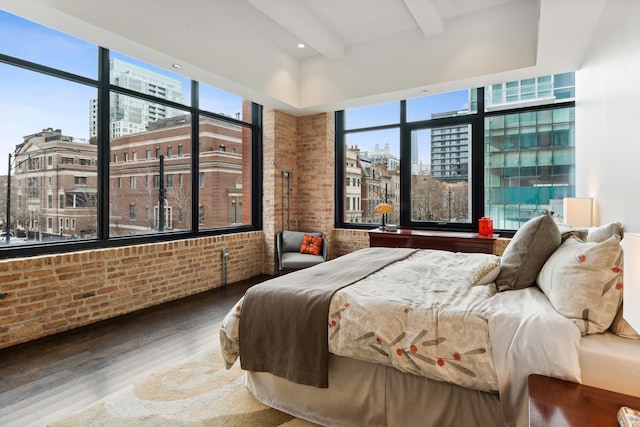 bedroom with a view of city, brick wall, and multiple windows