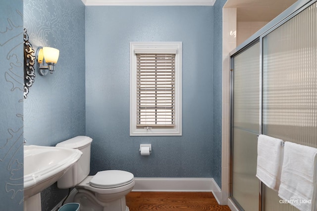 full bathroom with a tile shower, wood finished floors, a sink, toilet, and wallpapered walls
