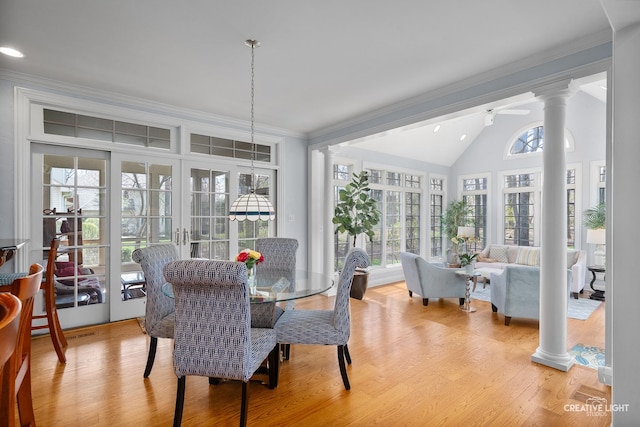 dining space featuring crown molding, lofted ceiling, ornate columns, french doors, and light wood-style flooring
