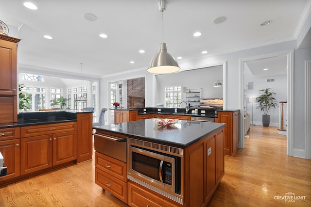 kitchen with light wood-type flooring, a warming drawer, stainless steel microwave, and a peninsula
