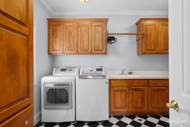 clothes washing area featuring ornamental molding, tile patterned floors, washing machine and clothes dryer, a sink, and cabinet space
